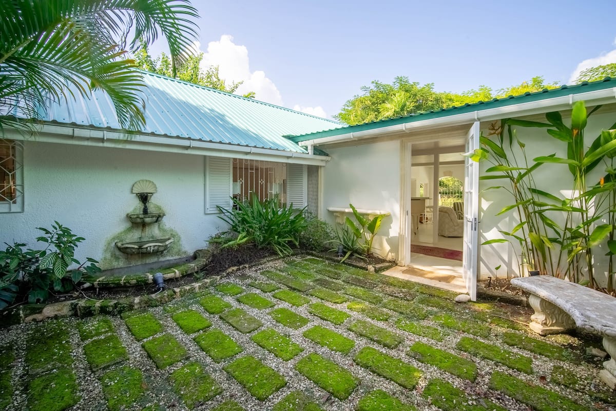 Private tropical courtyard with a fountain and grass-set stone path