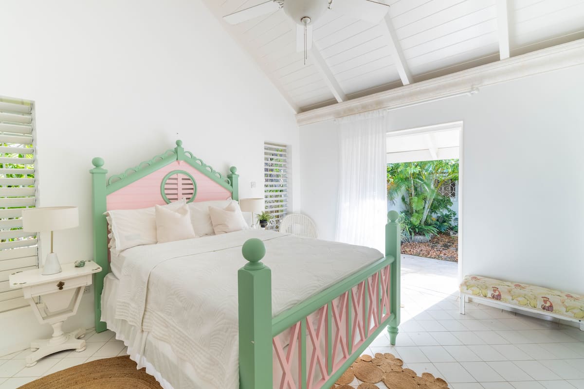 White bedroom with a green and shell-pink four-poster bed