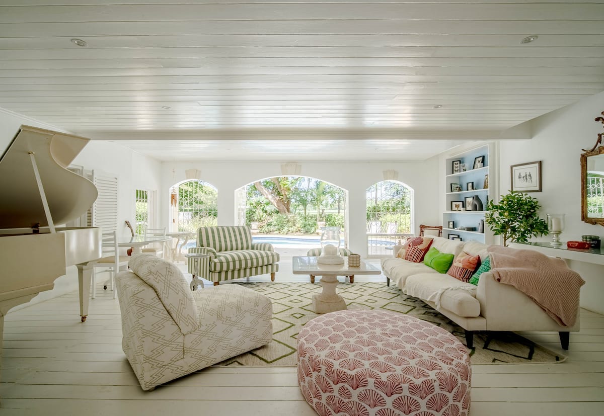 Open white living room with a grand piano and garden views